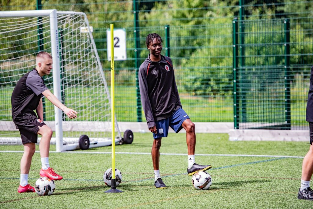 Sport apprentice smiling, with football under him
